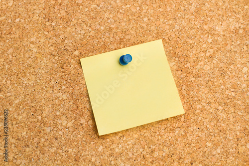 Papel adhesivo post it amarillo sobre pizarra de corcho. Vista de frente. Copy space