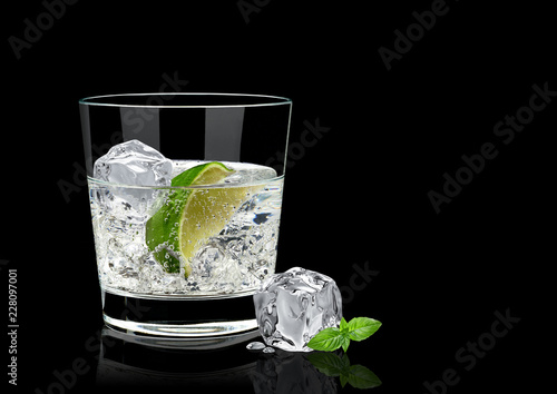 Vodka lime, mojito or gin tonic with lime wedge and ice in rocks glass on black background including clipping path