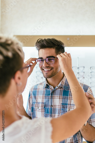 Canvastavla Attractive young couple in optical store buying glasses and smiling
