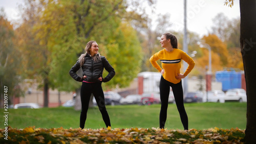 Girls warming up outside before training in park. Hands to the sides. Autumn. photo