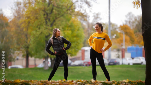 Girls in sweaters warming up outside before training in park. photo