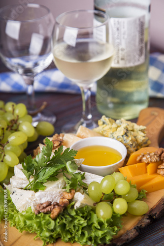 Cheese plate served with white wine, grape and nuts. Closeup