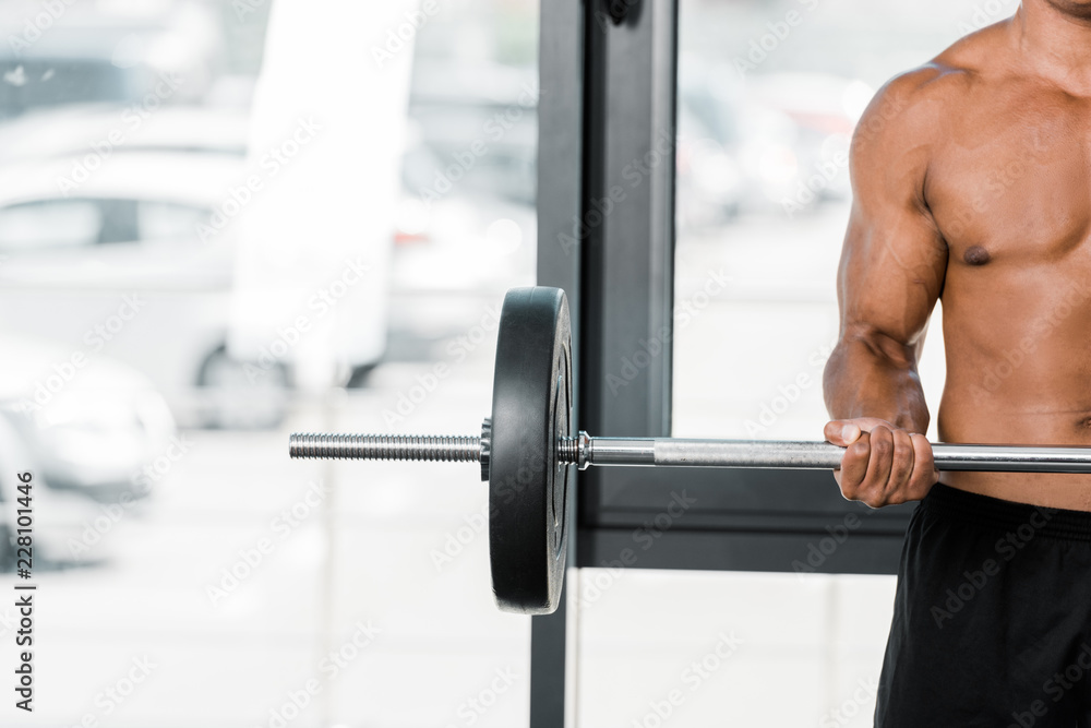 cropped shot of young muscular sportsman holding barbell in gym cropped shot of young muscular sportsman holding barbell in gym