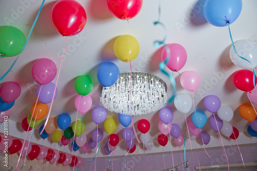 Colorfull balloons float on the white ceiling in the room for the party. Wedding or children birthday party decoration interior . Helium balloons . chandelier . candelabrum