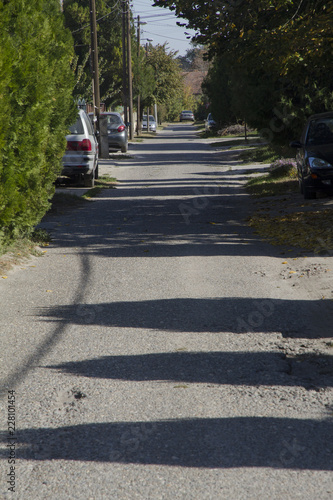 A perspective shot of a narrow street with shadow play on the asphalt road. Urban scene.