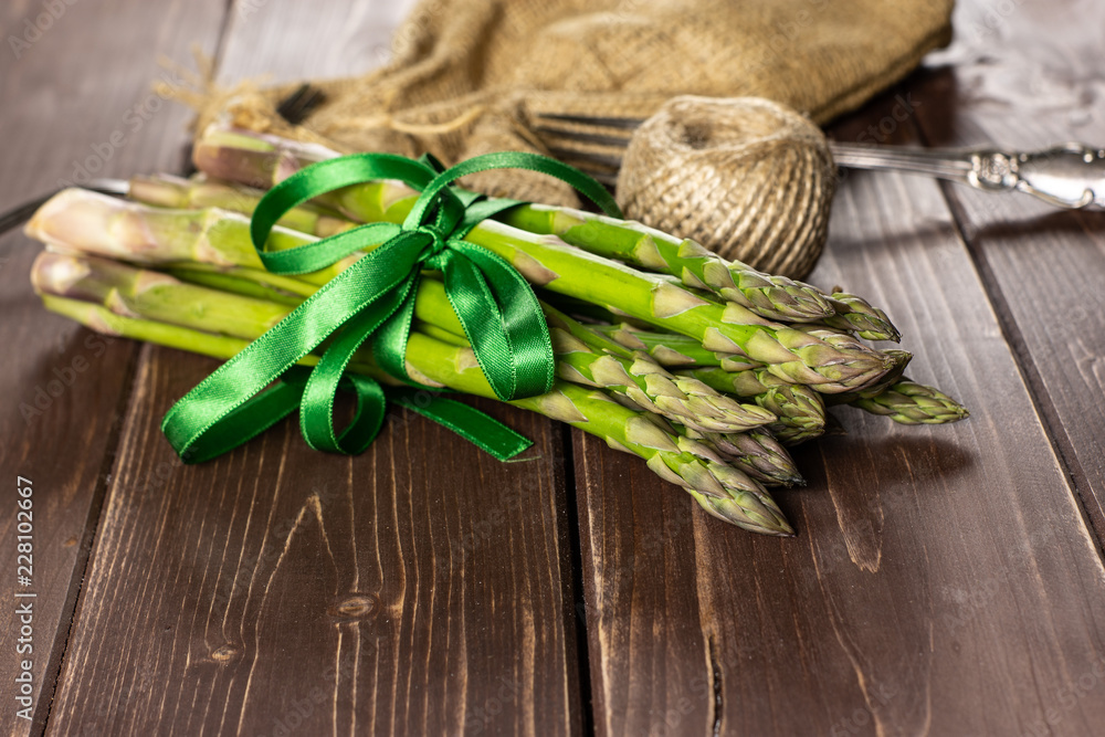 Bundle of lot of whole fresh green asparagus spear with jute cloth on brown wood Bundle of lot of whole fresh green asparagus spear with jute cloth on brown wood