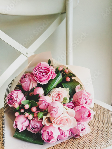 gift wrapt bouquet of pink rose on the white chair against the wall photo