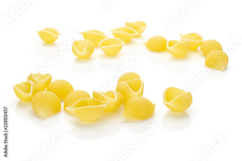Lot of whole raw yellow pasta conchiglie variety front focus isolated on white background