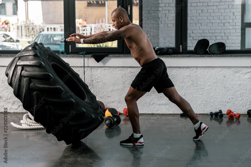 side view of muscular shirtless man exercising with tyre in gym Stock Photo Adobe Stock