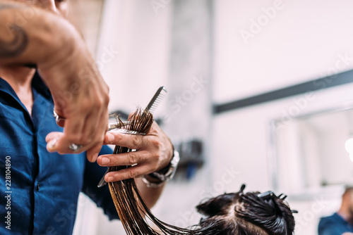 Professional male hairdresser cutting female customers hair. Close-up.