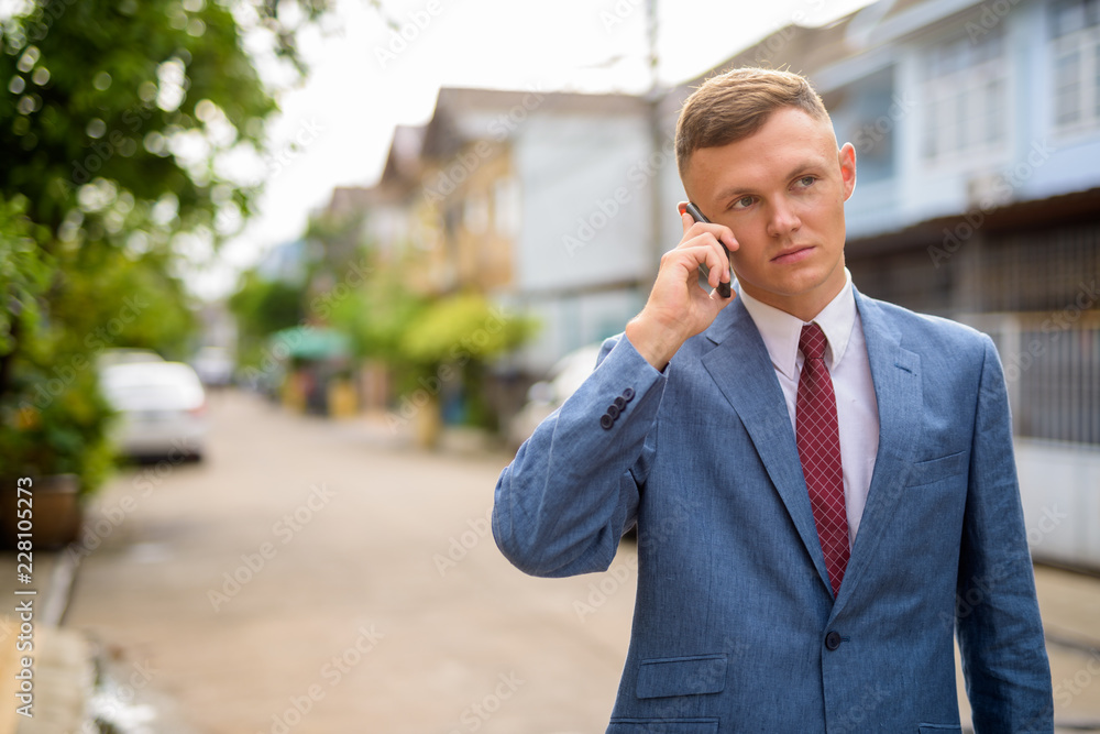 Young businessman using mobile phone in the streets outdoors Young businessman using mobile phone in the streets outdoors