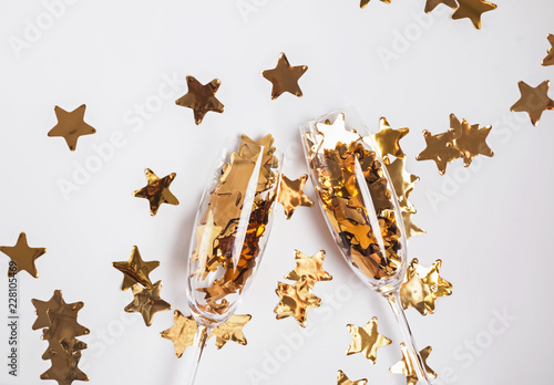 Golden confetti in champagne glasses on the white background.