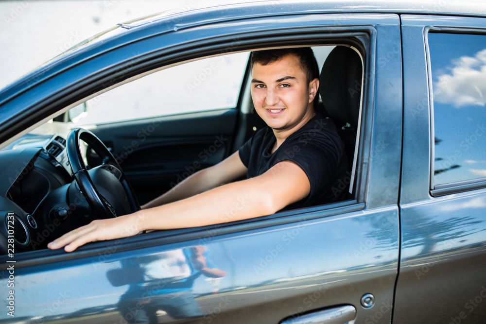Riding his new car. Side view of handsome young man driving his car and smiling Riding his new car. Side view of handsome young man driving his car and smiling