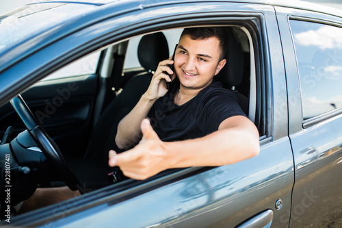 Young man talking on his phone and driving a car