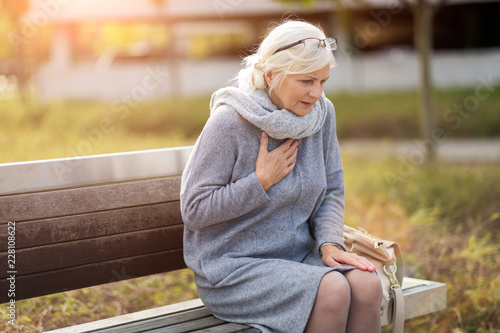 Vászonkép Senior Woman Suffering From Chest Pain While Sitting On Bench