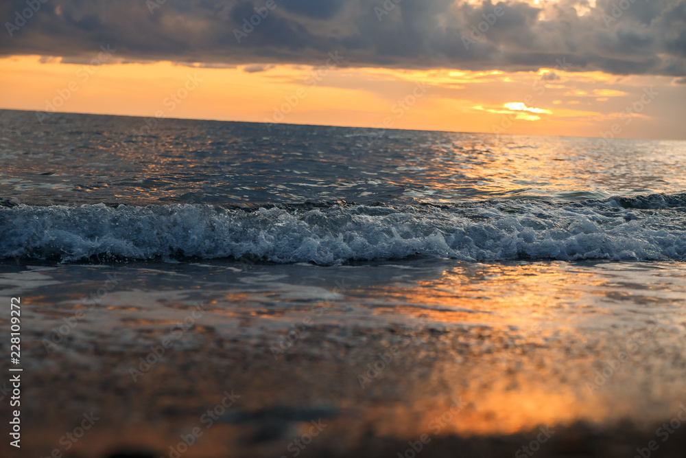 sunset at sea, bottom view, sand at sunset, waves with foam