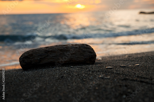 sunset at sea  bottom view  large dark sand  wooden piece ice next