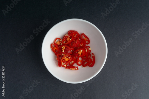 Red chili slices on dark background with selective focus and crop fragment