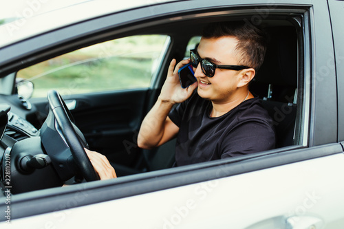 Young man talking on a mobile phone while driving car.