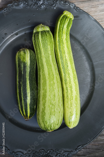 drei Gartenzucchinis auf einem schwarzen Teller photo