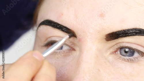 Professional make-up artist drawing eyebrows of beautiful client. Beauty and fashion concept photo