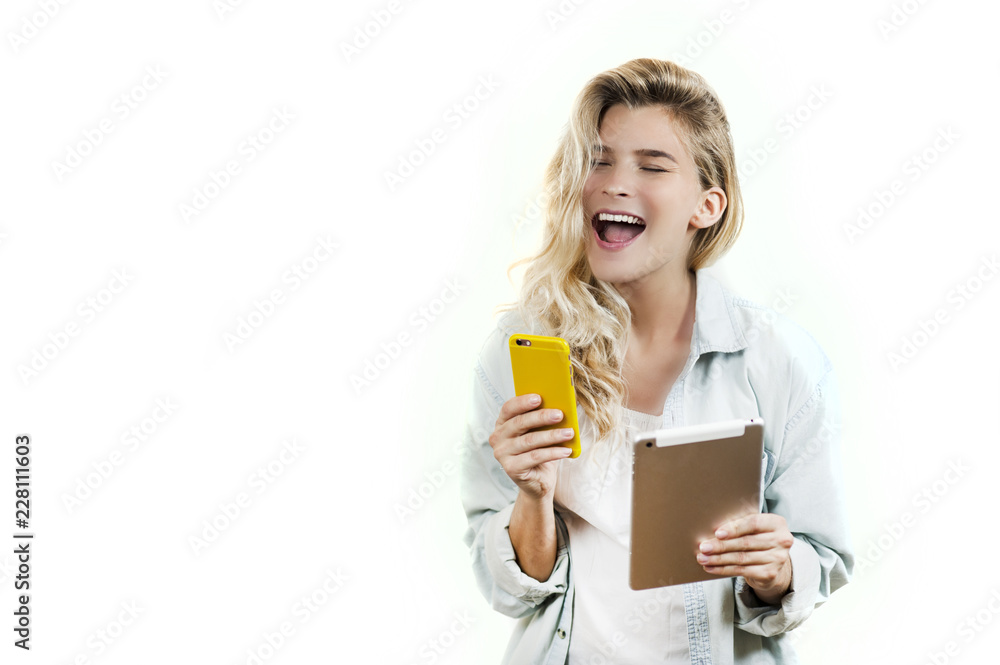 Young very beautiful business girl with a phone and ipad in her hands smiles and laughs at what she saw in on a white background Young very beautiful business girl with a phone and ipad in her hands smiles and laughs at what she saw in on a white background