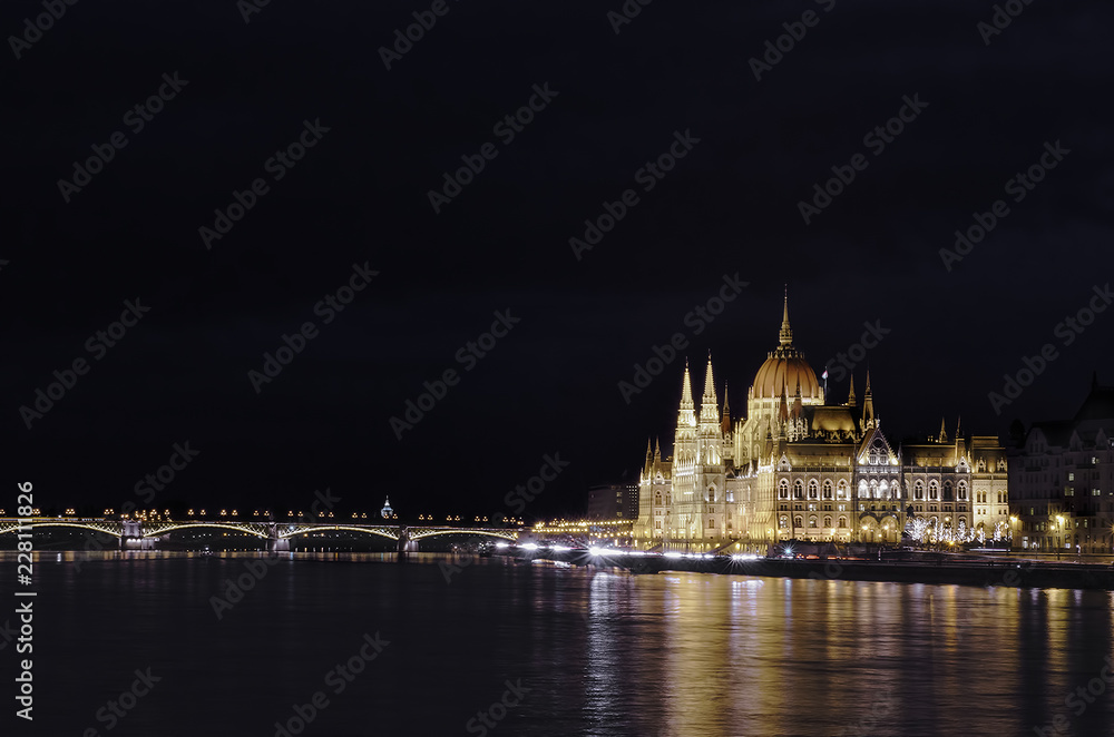 Night view of the illuminated building of the hungarian parliament in Budapest. A beautiful reflection of the parliament building on the Danube River. Winter city night landscape.