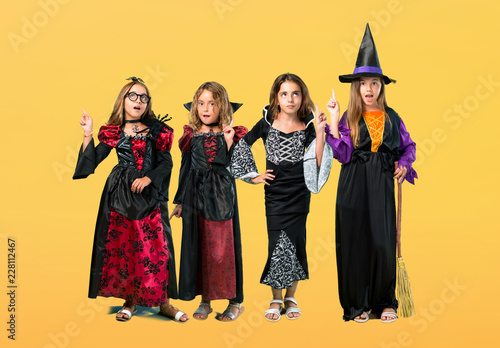 Set of Little girl dressed as a vampire for halloween holidays standing and thinking an idea on orange background
