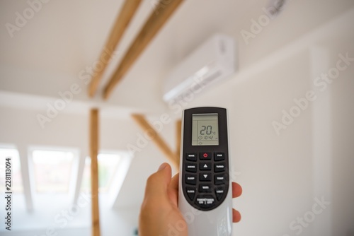 Man adjusting and regulating temperature on home air conditioner