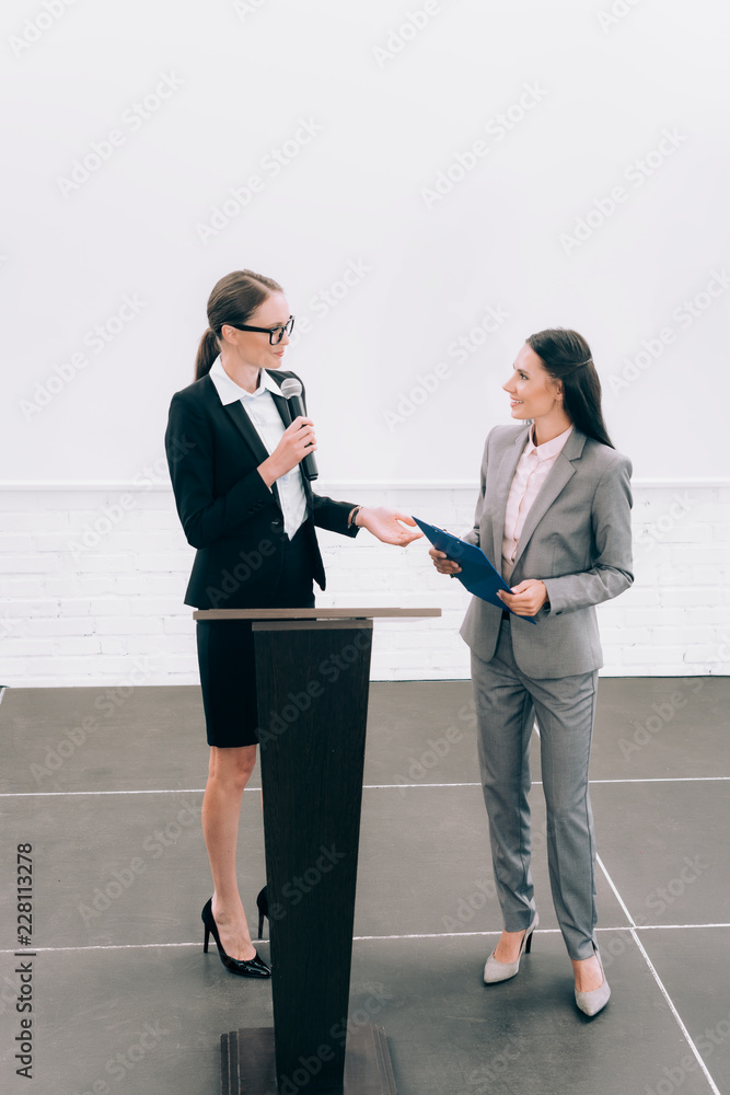 Fototapeta premium high angle view of attractive lecturer looking at smiling assistant during seminar in conference hall