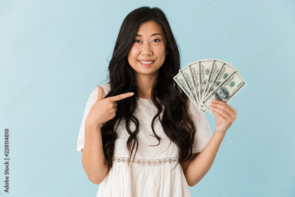 Beautiful woman isolated over blue background holding money. Beautiful woman isolated over blue background holding money.