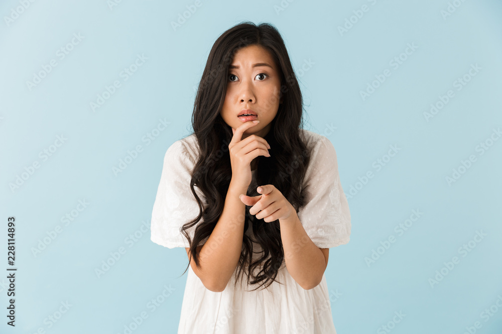 Thinking scared young asian beautiful woman posing isolated over blue background. Thinking scared young asian beautiful woman posing isolated over blue background.