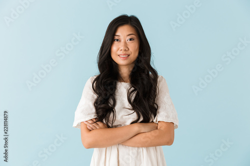 Happy young asian beautiful woman posing isolated over blue background. © Drobot Dean