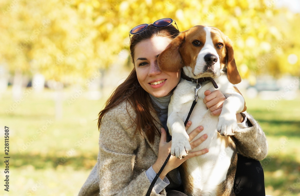Attractive girl hugging her beagle dog in autumn park Attractive girl hugging her beagle dog in autumn park