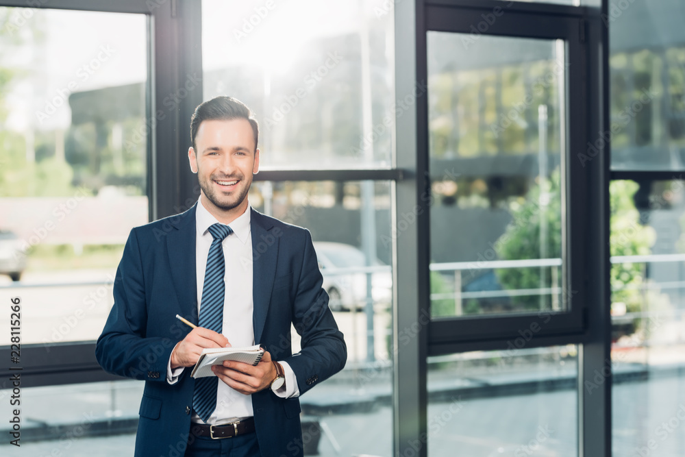 portrait of smiling businessman with notebook in conference hall portrait of smiling businessman with notebook in conference hall