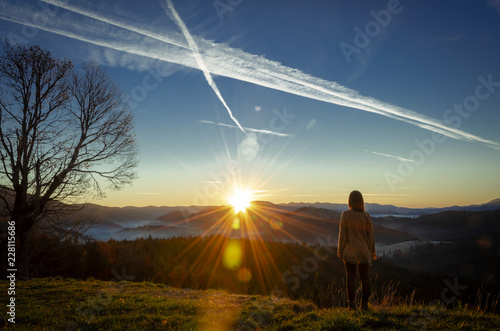 cheering woman hiker open arms at mountain peak,Young girl spreading hands with joy and inspiration facing the sun,Girl enjoying the freedom in mountian mist on sunrise