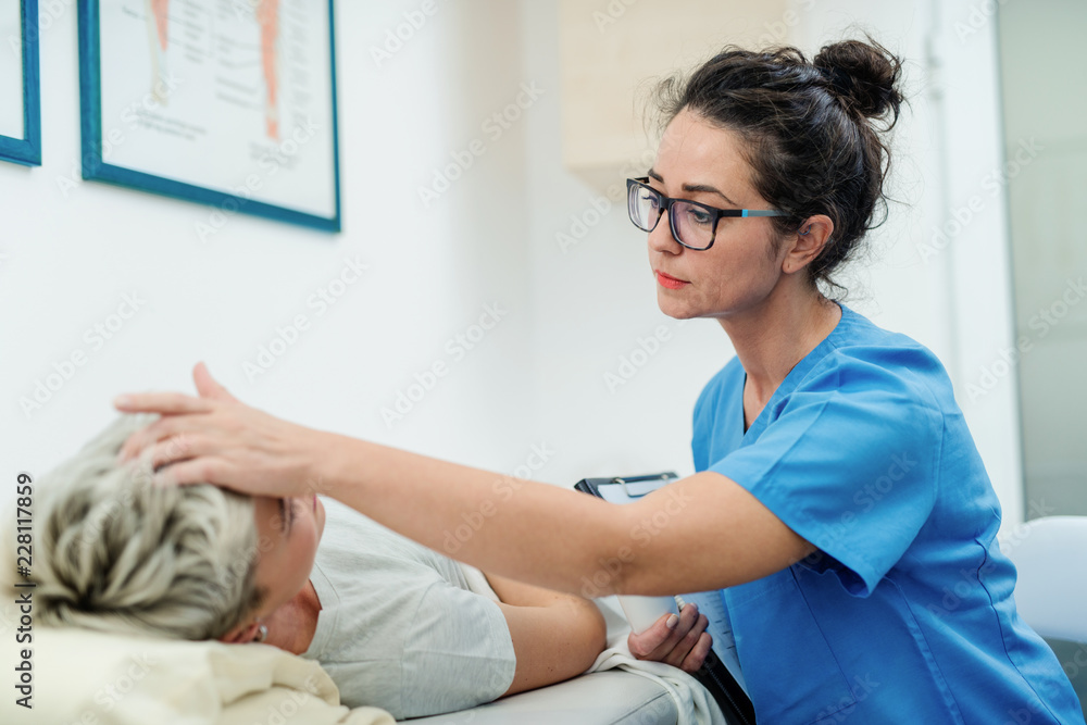 Sick woman lying down in bed and doctor checking temperature by putting hand on forehead. Sick woman lying down in bed and doctor checking temperature by putting hand on forehead.