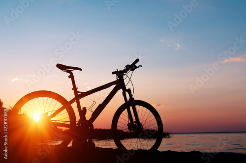 Beautiful close up scene of bicycle at sunset, sun on blue sky with vintage colors, silhouette of bike forward to sun