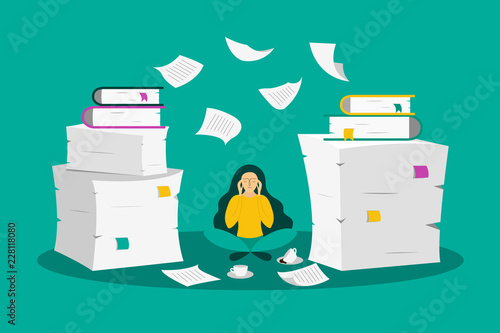 Young woman sits between the stacks of paper photo
