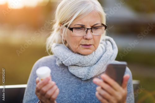 Woman holding smartphone and pill bottle photo