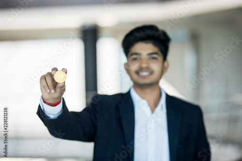 Indian business man in suit with golden bitcoin in modern office