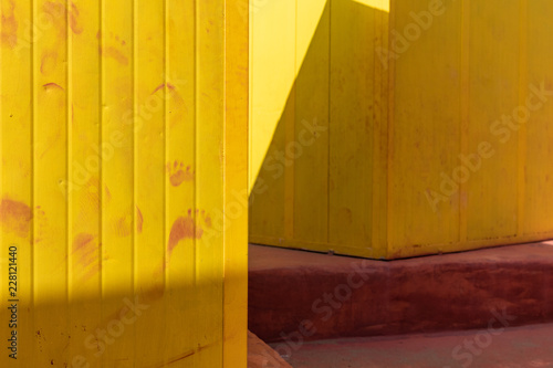 Beautiful yellow Bathing houses on sandy beach. Empty shelters on a sunny but moody day. Seaside architecture, colored paint, maze like labyrinth. Homelessness and lonely places. © Edward R