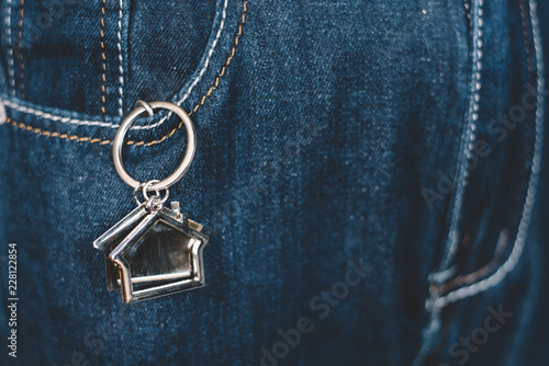 House shape keychain or key holder in a jeans pocket. Concept of own a house and home financing