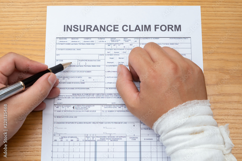 Obraz premium man with a wrapped hand filling up an insurance claim form medical and insurance concept no logo or trademark
