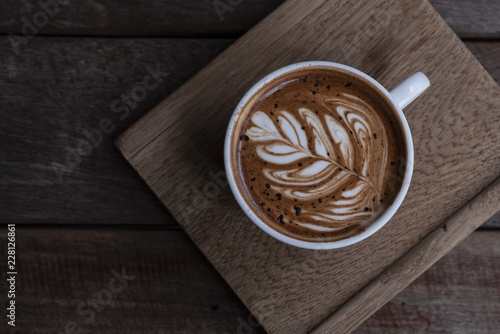 Nice shape of latte art coffee serve on wooden plate