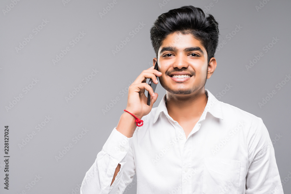 Young indian handsome business man have a conversation on phone isolated on gray Young indian handsome business man have a conversation on phone isolated on gray