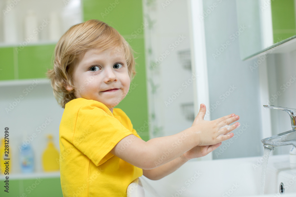 little boy in a bathroom washes hand with soap little boy in a bathroom washes hand with soap