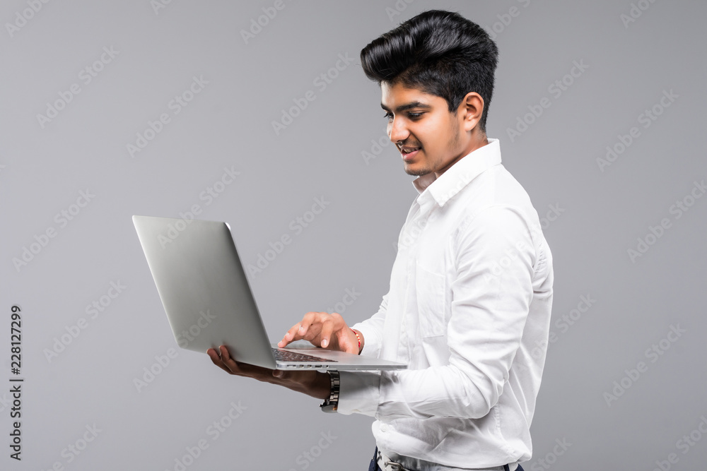 Young indian man with laptop isolated on gray background