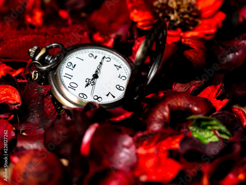 Golden vintage pocket watch put on a wooden table with red dried flowers with aroma