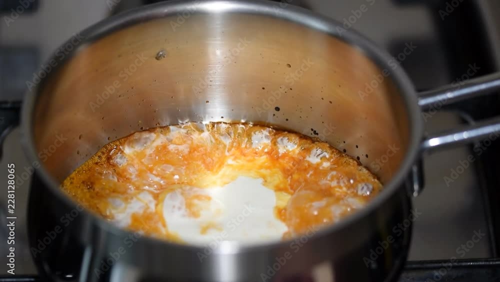 Cooking caramel sauce. Pouring whipping cream in the caramel. Cooking caramel sauce. Pouring whipping cream in the caramel.